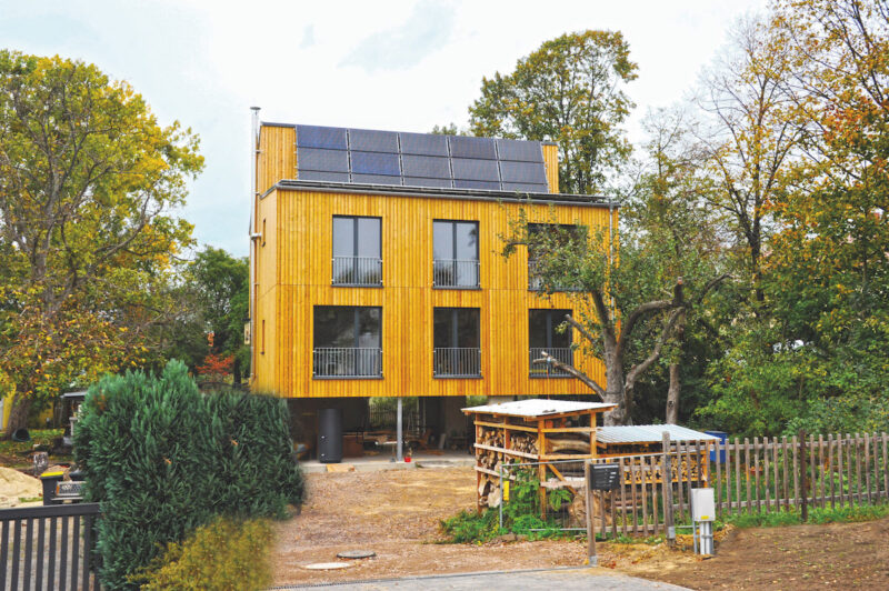 Ein Haus mit einer Holzverkleidung, oben auf dem Dach fast senkrecht installiert eine Solarthermie-Anlage.