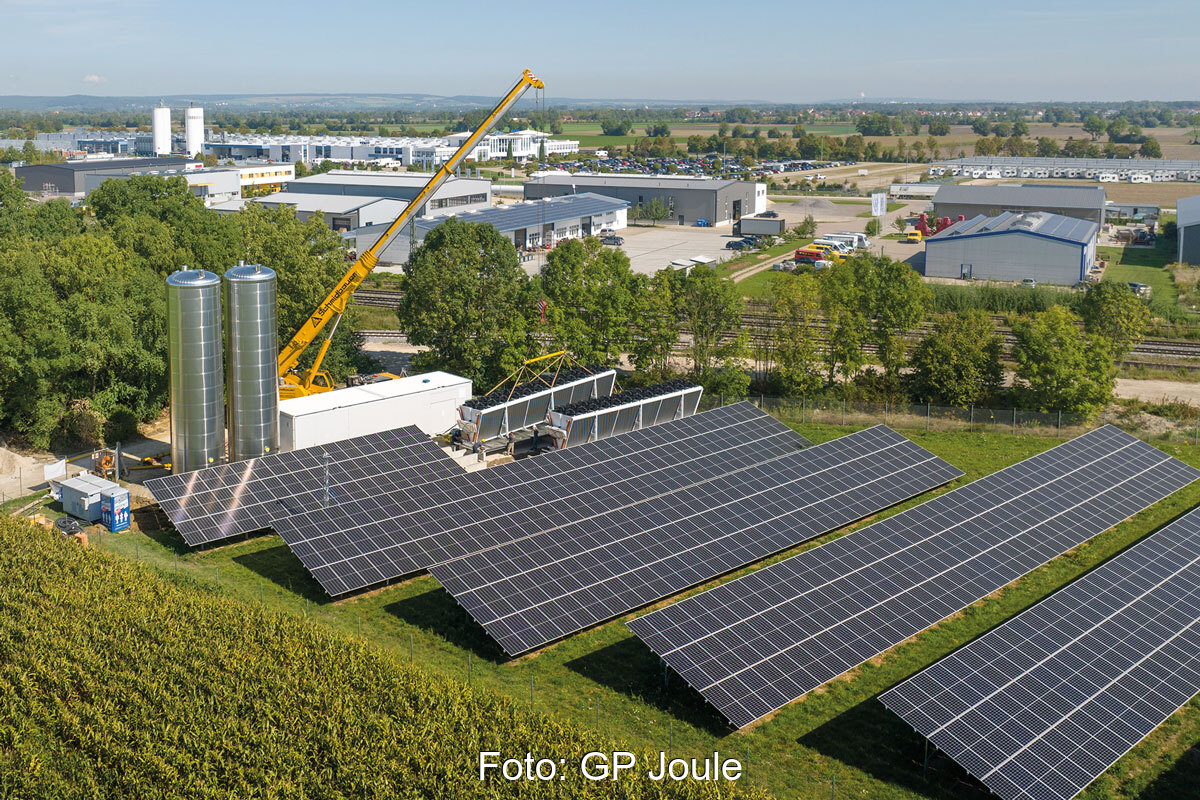 Luftbild einer Heizzentrale aus Photovoltaik-Freiflächenanlage und Luftwärmepumpe mit zwei Speichern in Mertingen.