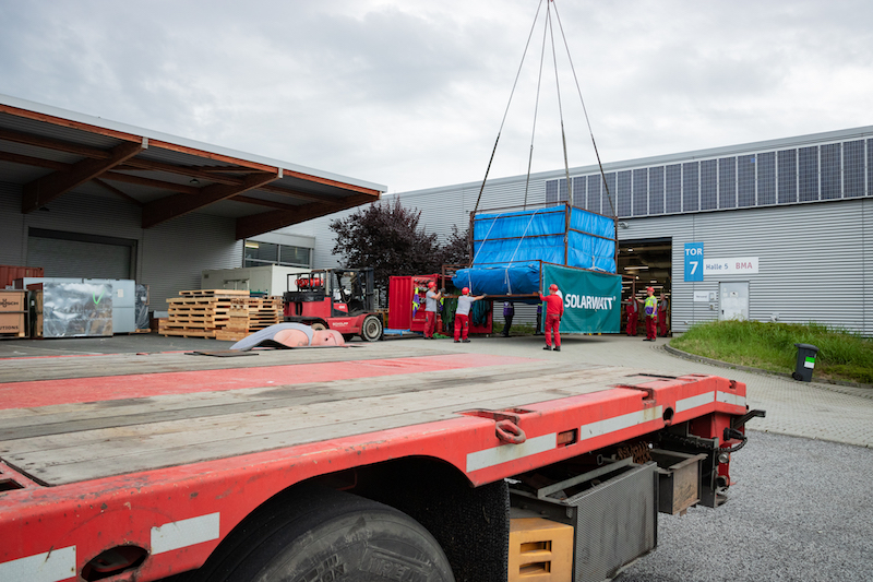 Container mit Laminatoren werden mit Kran in Modulproduktion von Solarwatt gebracht