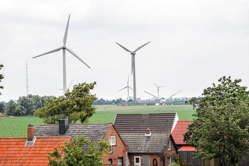 Windenergieanlagen in Norddeutschland hinter Gebäudedächern