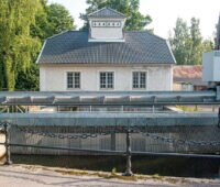 Kleines, historisches Wasserkraft mit Rechen im Vordergrund