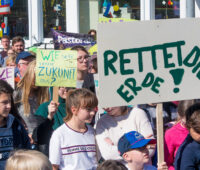 Schüler zeigen auf Klimademo selbstgebastelte Transparente. Ganz vor ein Plakat "Rettet die Erde!"