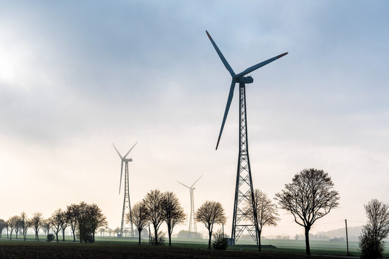 Windenergieanlagen auf Gittermasten im Gegenlicht