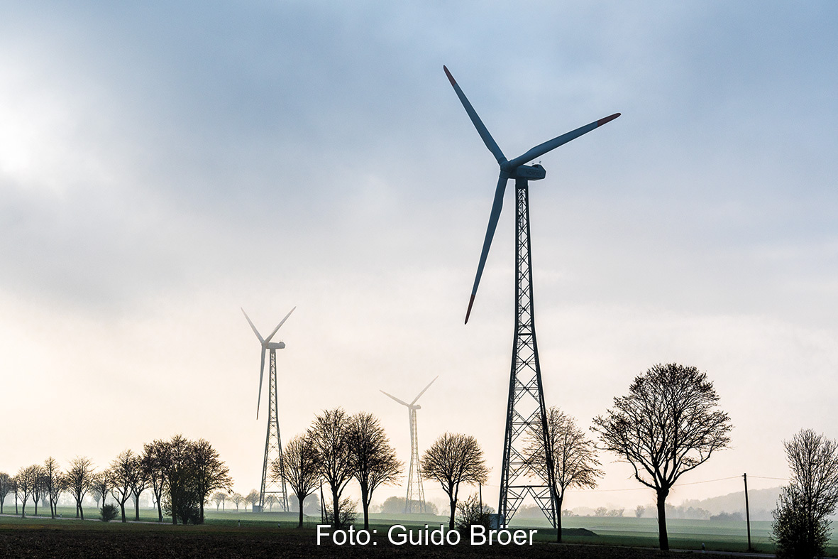 Windenergieanlagen auf Gittermasten im Gegenlicht