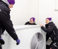 Drei Mitarbeiter von 1Komma5° bei der Montage einer Wärmepumpe.