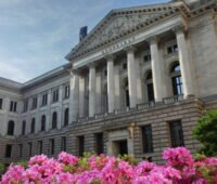 Zu sehen ist das Gebäude des Bundesrates mit pinken Blüten im Vordergrund.