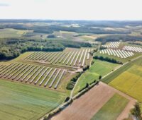 Luftbild eines Solarparks in grüner Umgebung.