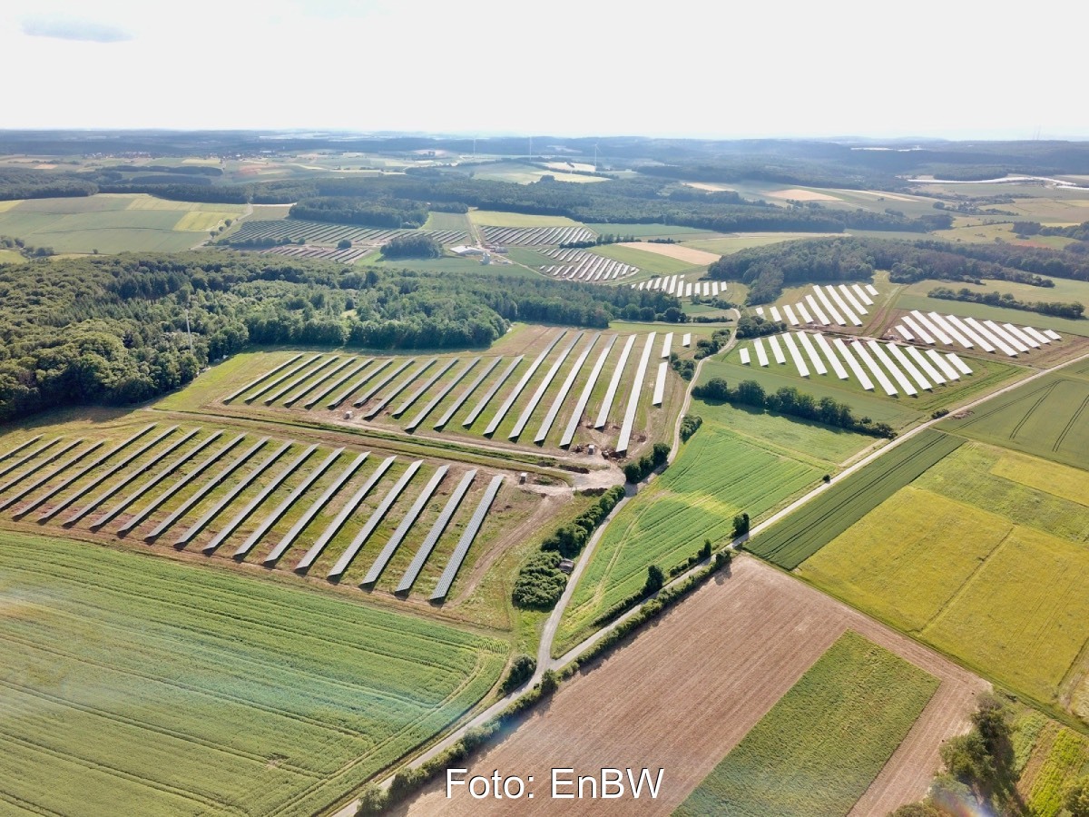 Luftbild eines Solarparks in grüner Umgebung.