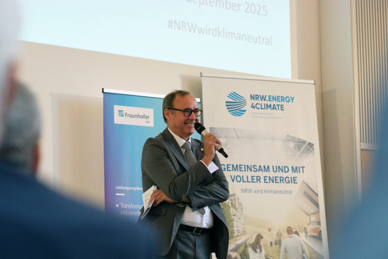 Redner mit Mikro auf der Konferenzbühne aus Perspektive des Publikums