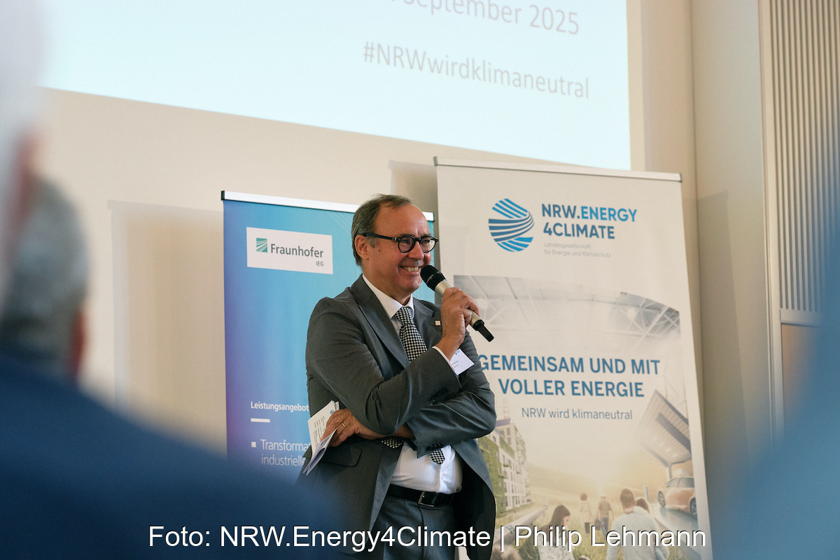 Redner mit Mikro auf der Konferenzbühne aus Perspektive des Publikums