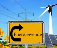 Ein animiertes Bild zeigt ein Verkehrsschild, das auf die Energiewende zeigt udn im Hintergrund Wind, Solarenergie udn Strommasten.