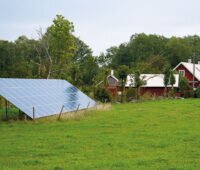 kleine Freiflächensolaranlage auf einer Wiese vor einem Wohnhaus.