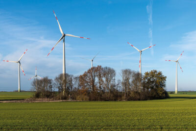Windenergie-Park hinter Baumgruppe - Enercon-Anlagen vom Typ E 101 und E 92.