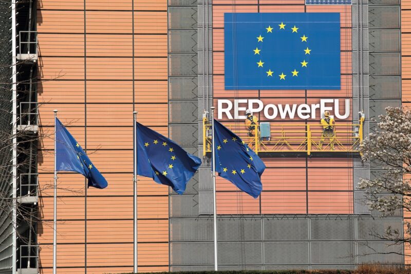 Gebäude der EU-Kommission - rotes Gebäude mit blauen Flaggen davor und blauem Banner.