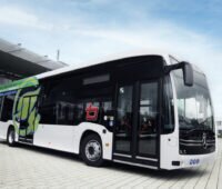 Ein Elektro-Bus fährt von schräg links ins Bild.