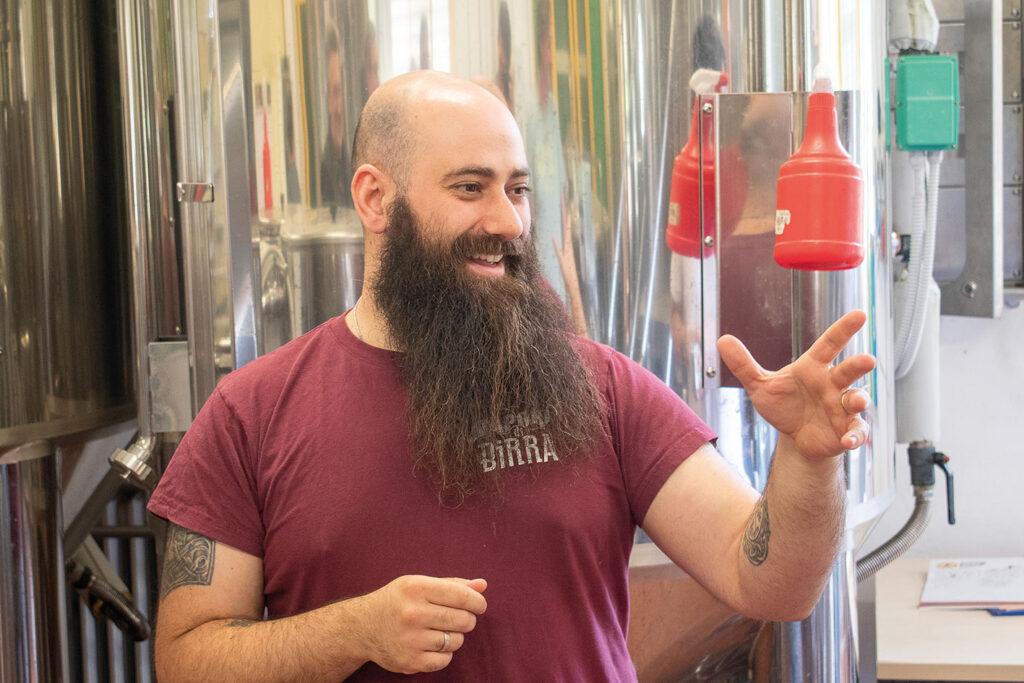 Portraitfoto von Denny Pretolani, dem Braumeister der Brauerei Vapori di Birra vor Biertanks aus Edelstahl.