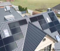Zu sehen sind AIKO ABC-Solarmodule auf einem Einfamilienhaus mit dunklen Dachziegeln
