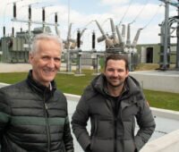Mathias und Martin Niedzwetzki vor Trafos und großen Isolatoren im neuen Umspannwerk in Bartow.