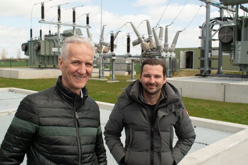 Mathias und Martin Niedzwetzki vor Trafos und großen Isolatoren im neuen Umspannwerk in Bartow.