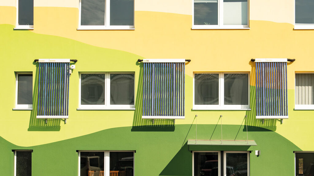 Bunte Fassade eines Bürogebäudes von Akotec mit drei senkrecht montierten Röhrenkollektoren.