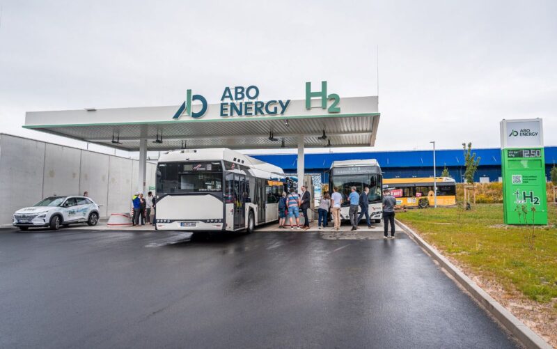 Busse tanken Wasserstoff an einer Tankstelle mit Besuchern.