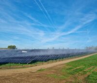 Ein Freiflächen-Solarpark unter blauem Himmel mit Schlierenwolken.