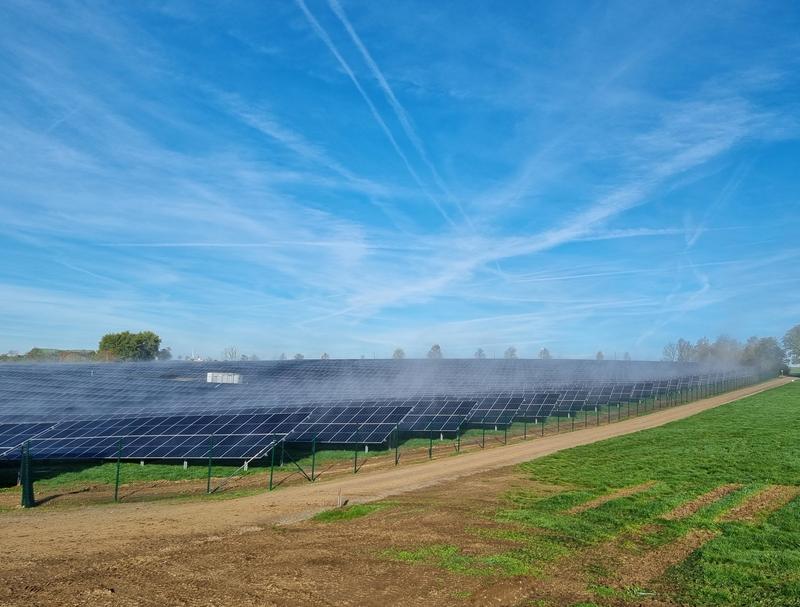 Ein Freiflächen-Solarpark unter blauem Himmel mit Schlierenwolken.