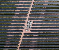 Ein Hybridkraftwerk aus Photovoltaik und Windenergie auf grüner Wiese unter blauem Himmel.