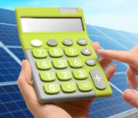 Ein Taschenrechner vor Photovoltaik-Anlage als Symbol für den Wertschöpfungsrechner für erneuerbare Energien.