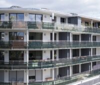 Mehrstöckiges Wohngebäude mit umlaufenden organischen PV-Modulen an den Balkonen.