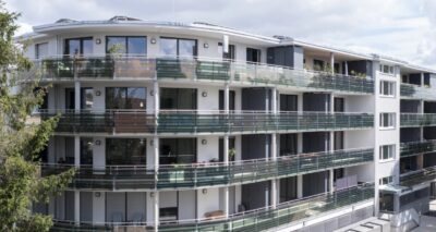 Mehrstöckiges Wohngebäude mit umlaufenden organischen PV-Modulen an den Balkonen.