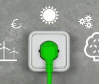 Im Bild ein grüner Stecker in Steckdose, der neue Stichtag für Stromkennzeichnung ist an 2025 der 1. Juli.