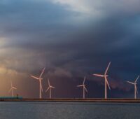 Windkraftanlagen am Meer vor dunklen Wolken.