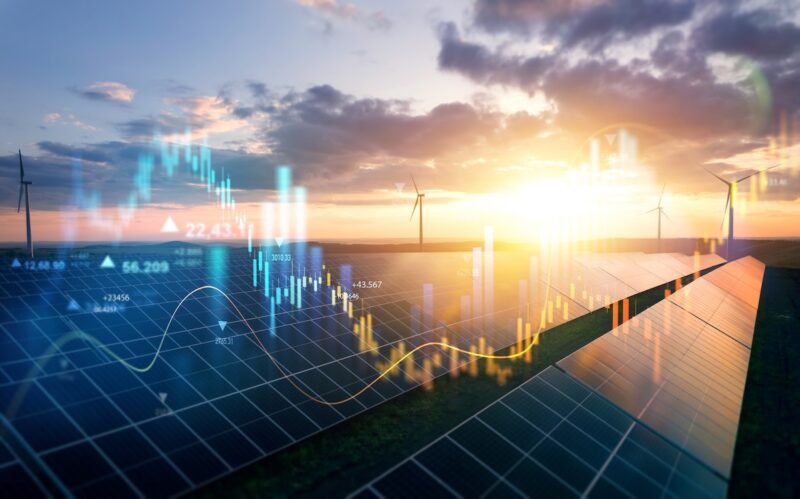 Eine Photovoltaikfreiflächenanlage, die im Dunklen liegt. Teils Wolken, teils Sonne. Darüber in Bild montiert auf- und absteigende grafische Kurven als Symbol für den Photovoltaikmarkt.