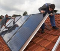 Handwerker installieren eine Solarthermie-Anlage auf einem Dach. Symbolbild für BAFA-Förderung - BEG