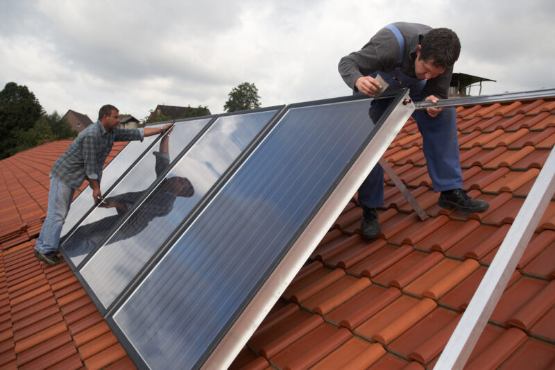 Handwerker installieren eine Solarthermie-Anlage auf einem Dach. Symbolbild für BAFA-Förderung - BEG