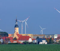 Ortsansicht mit Windkraftanlagen im Hintergrund