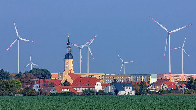 Ortsansicht mit Windkraftanlagen im Hintergrund