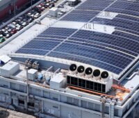 Gebäude eines Rechenzentrums. Auf dem Dach sind PV-anlagen und große Ventilatoren von Kältemaschinen zu sehen.