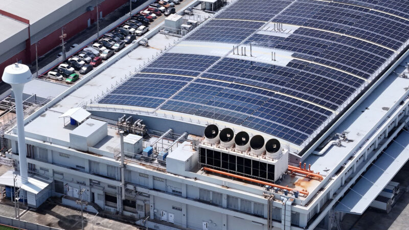 Gebäude eines Rechenzentrums. Auf dem Dach sind PV-anlagen und große Ventilatoren von Kältemaschinen zu sehen.