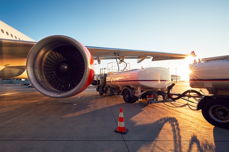 Blick auf Flugzeug von hinten mit daneben stehendem Tankwagen. Symbolbild für grüne Flugzeugkraftstoffe, SAF, E-Fuels.