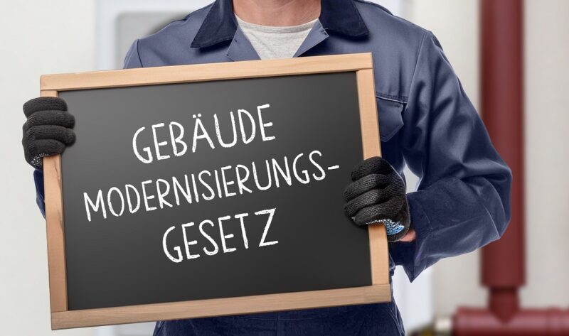Ein Mensch hält eine Tafel mit der Aufschrift Gebäudemodernisierungsgesetz.