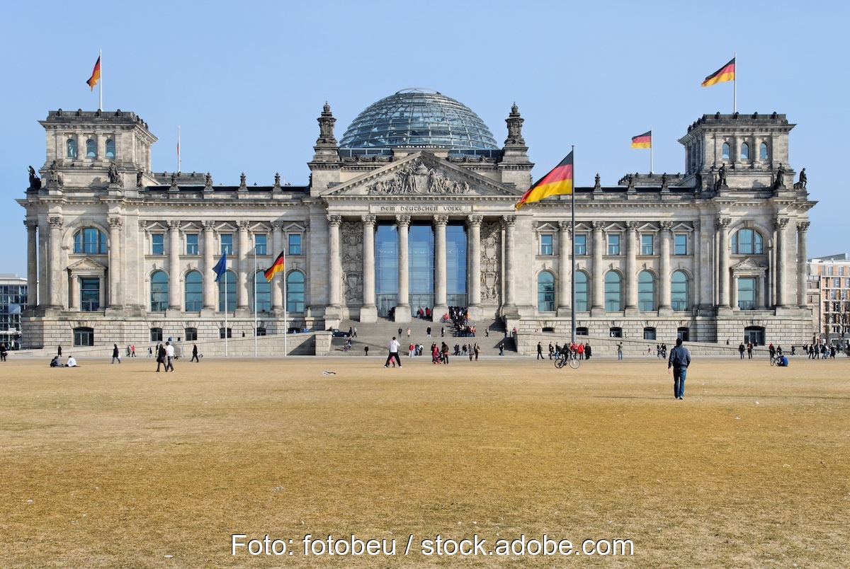 Ansicht des Bundestags, im Vordergrund die davor liegende Wiese. Vor dem Bundestag flanieren Menschen