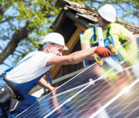 Monteure befestigen Photovoltaikmodule auf einem Schrägdach