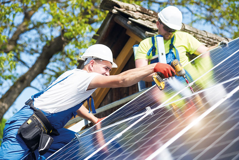 Monteure befestigen Photovoltaikmodule auf einem Schrägdach