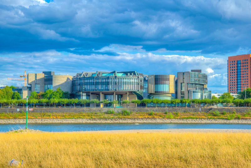 Landtagsgebäude von NRW in Düsseldorf von der anderen Rheinseite aus betrachtet mit dunklen Wolken über dem Gebäude