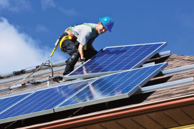 Handwerker verlegt Photovoltaikmodule auf einem Ziegeldach - Symbolbild für die Solarpflicht
