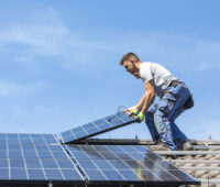 Installateure auf einem Dach montieren oder demontieren PV-Module