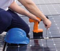 Handwerker verschraubt Photovoltaik-Module auf einem Dach