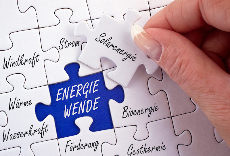 Puzzlespiel zur Energiewende. Das Teil zur Solarenergie wird in einer Hand gehalten